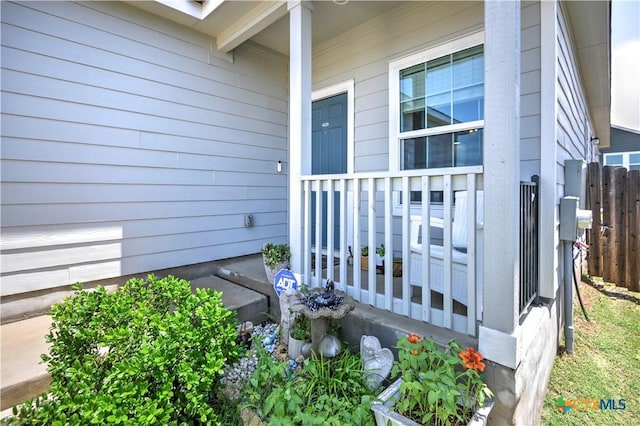 property entrance with covered porch and fence