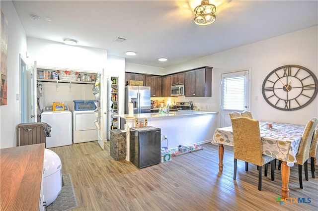 kitchen featuring appliances with stainless steel finishes, independent washer and dryer, dark brown cabinets, light wood finished floors, and light countertops