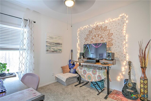 carpeted office space with a ceiling fan and baseboards