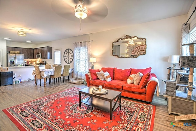 living room with a ceiling fan, light wood-style flooring, and baseboards
