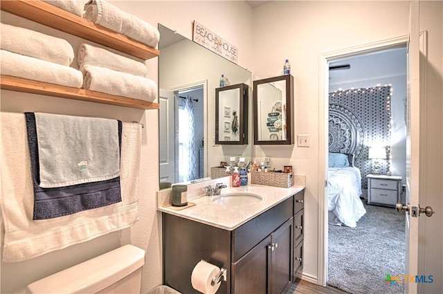 ensuite bathroom featuring toilet, vanity, and wood finished floors