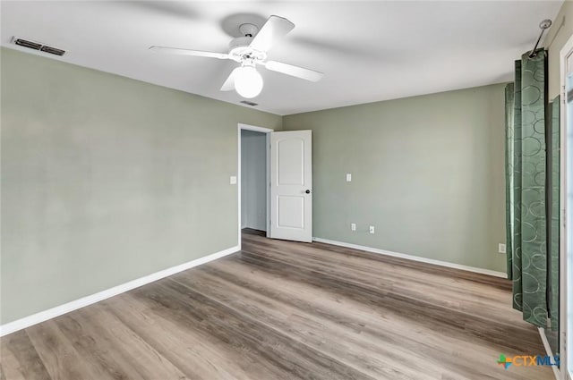 unfurnished bedroom featuring a ceiling fan, visible vents, baseboards, and wood finished floors