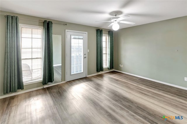 unfurnished room with ceiling fan, wood finished floors, and baseboards