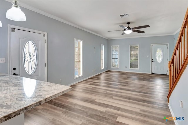 foyer entrance featuring crown molding, visible vents, wood finished floors, baseboards, and stairs