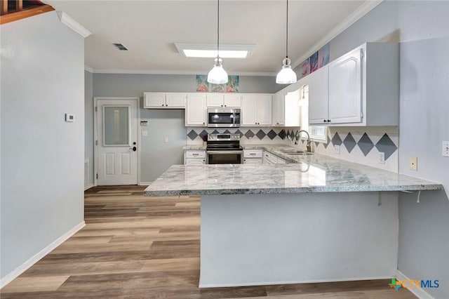 kitchen featuring a peninsula, appliances with stainless steel finishes, white cabinets, and decorative light fixtures