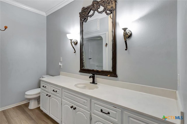 bathroom featuring toilet, ornamental molding, wood finished floors, and vanity