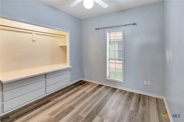 unfurnished bedroom with a ceiling fan, baseboards, and wood finished floors