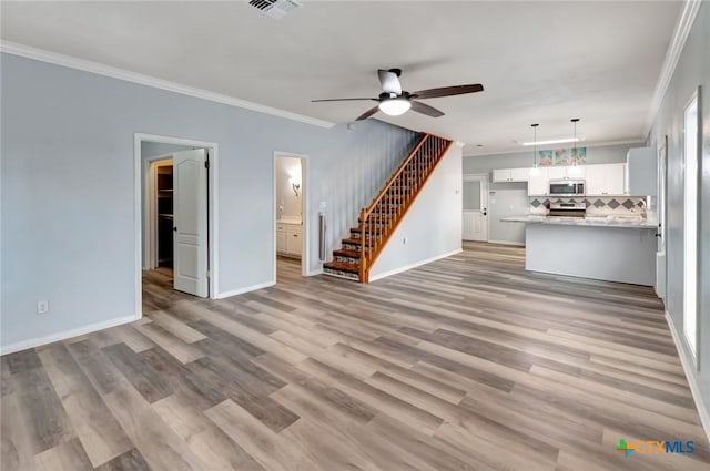 unfurnished living room with baseboards, visible vents, light wood-style flooring, stairway, and crown molding