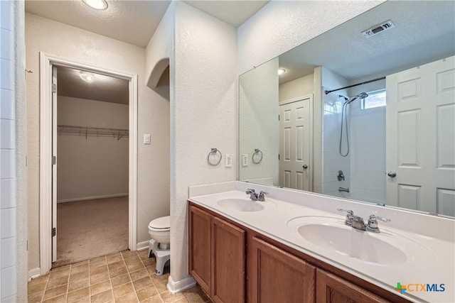 10122 Divine Breeze, San Antonio, TX 78251 - bathroom with a shower, double vanity, a textured wall, a spacious closet, and a textured ceiling