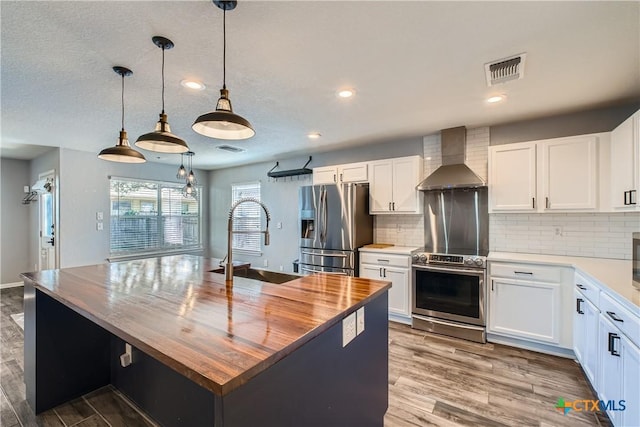 10122 Divine Breeze, San Antonio, TX 78251 - kitchen with wall chimney range hood, stainless steel appliances, wood finished floors, butcher block countertops, and decorative backsplash