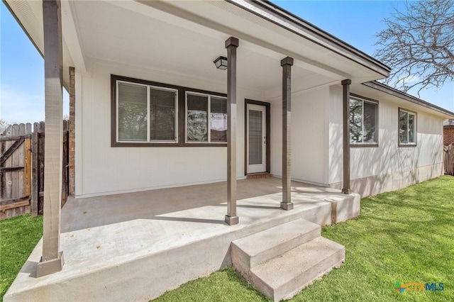 property entrance with a lawn and fence