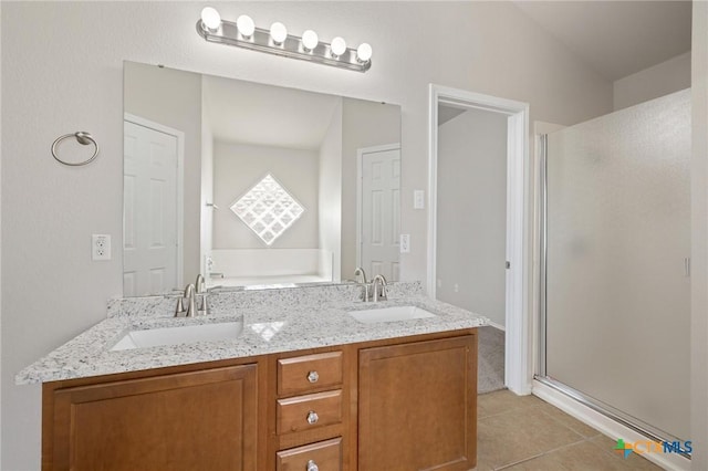 bathroom with double vanity, a shower stall, a sink, and tile patterned floors