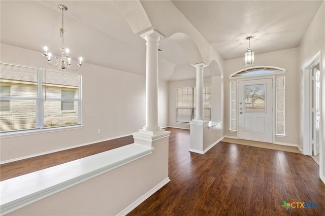 entrance foyer with baseboards, an inviting chandelier, wood finished floors, and ornate columns