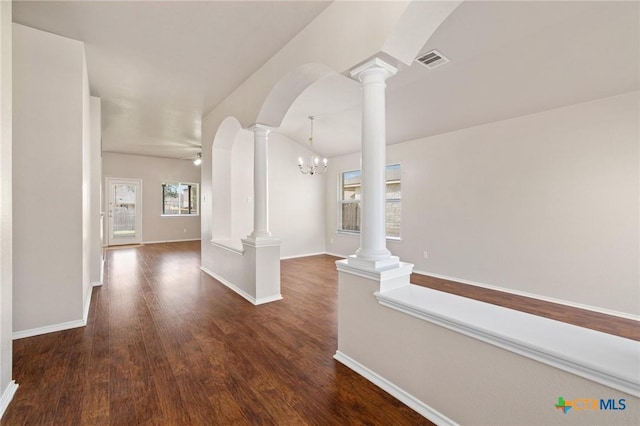 unfurnished room featuring dark wood-style floors, decorative columns, visible vents, and ceiling fan with notable chandelier