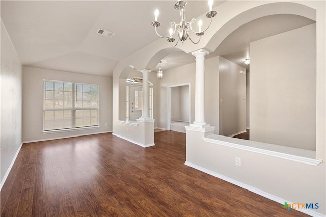 empty room featuring arched walkways, decorative columns, visible vents, vaulted ceiling, and wood finished floors