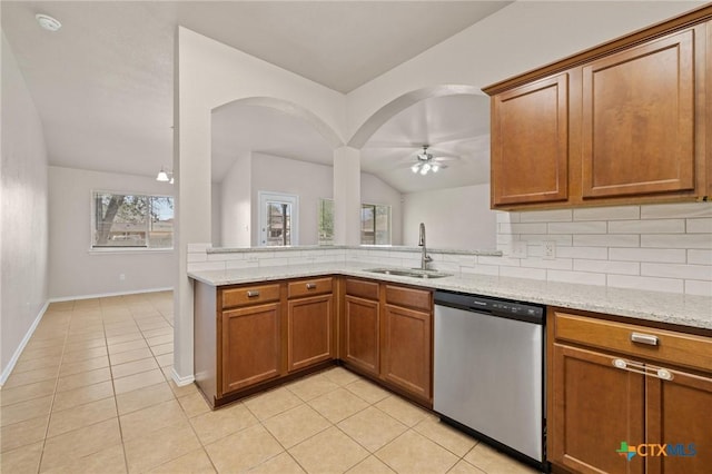 kitchen featuring tasteful backsplash, stainless steel dishwasher, light tile patterned flooring, vaulted ceiling, and a sink