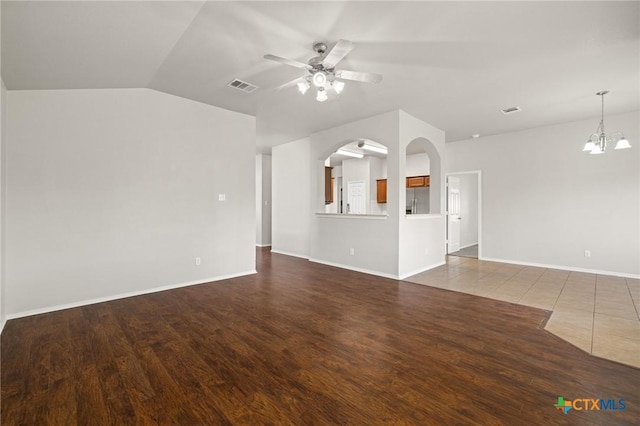 unfurnished living room featuring visible vents, dark wood finished floors, arched walkways, and ceiling fan with notable chandelier