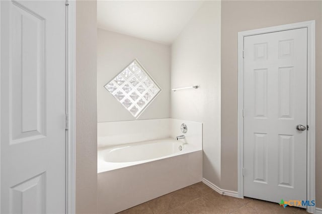 full bathroom with baseboards, a bath, and tile patterned floors