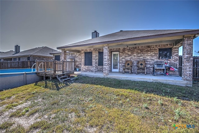 rear view of house with a yard and a swimming pool side deck