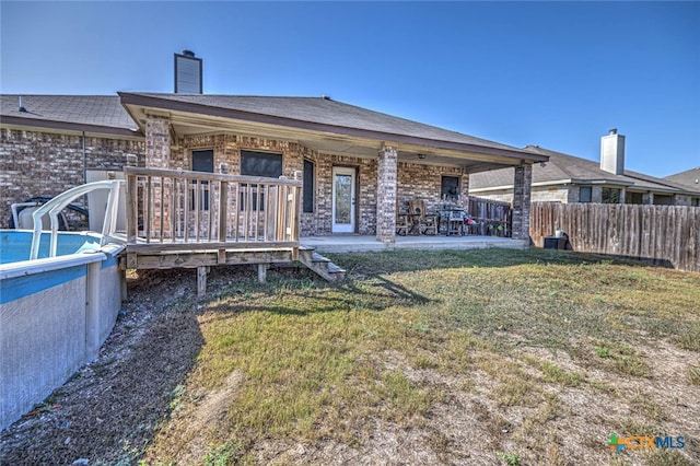 rear view of property featuring a lawn and a fenced in pool