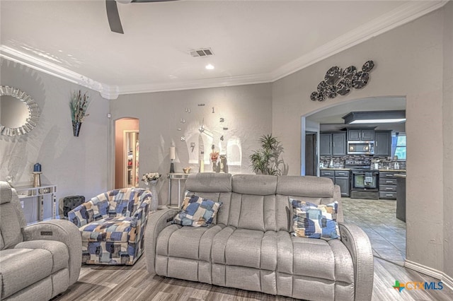 living room featuring light hardwood / wood-style floors, ceiling fan, and crown molding