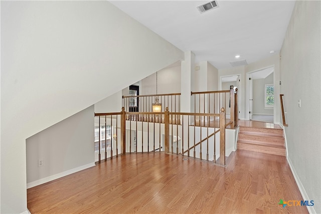 interior space featuring visible vents, vaulted ceiling, baseboards, and wood finished floors