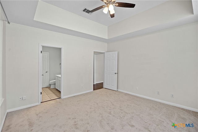 unfurnished bedroom featuring baseboards, a raised ceiling, visible vents, and light colored carpet