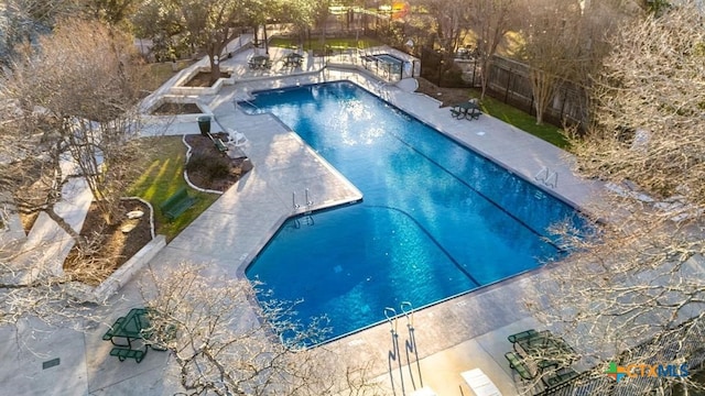 community pool with a patio area and a fenced backyard