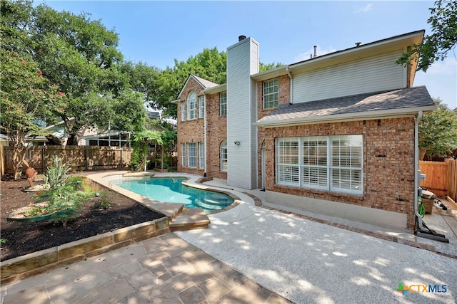 back of house featuring a fenced backyard, brick siding, a fenced in pool, a chimney, and a patio area