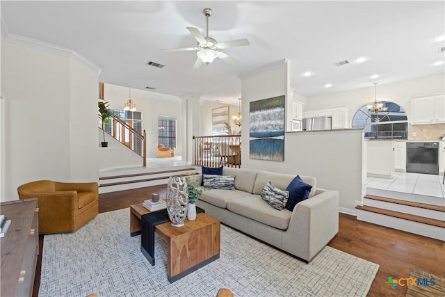 living area featuring stairs, light wood finished floors, ornamental molding, and visible vents