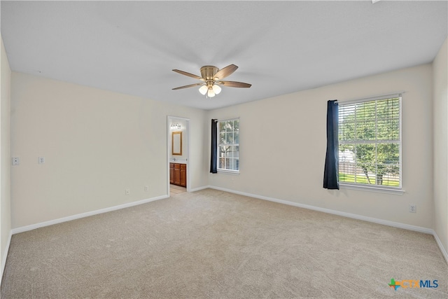 spare room featuring a ceiling fan, light carpet, and baseboards