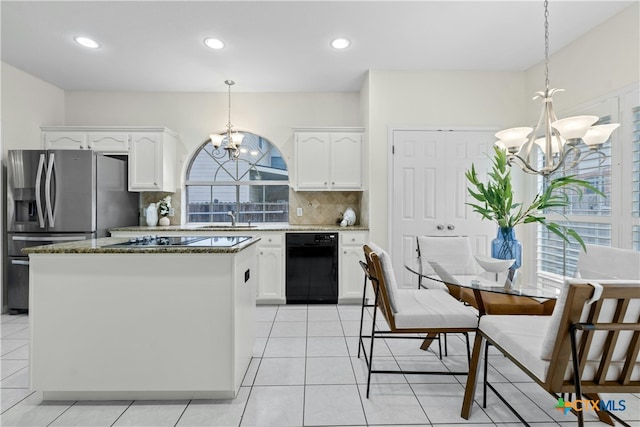 kitchen featuring backsplash, an inviting chandelier, stone countertops, a sink, and black appliances