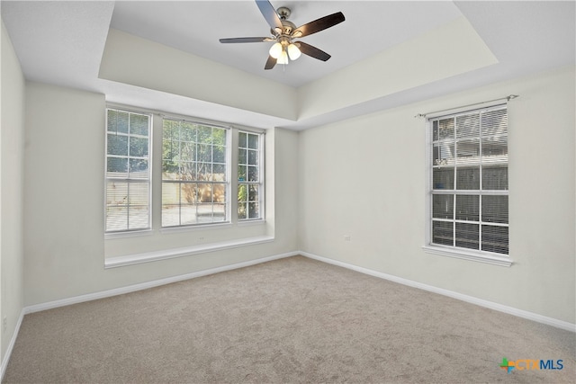 spare room with baseboards, a tray ceiling, ceiling fan, and carpet flooring