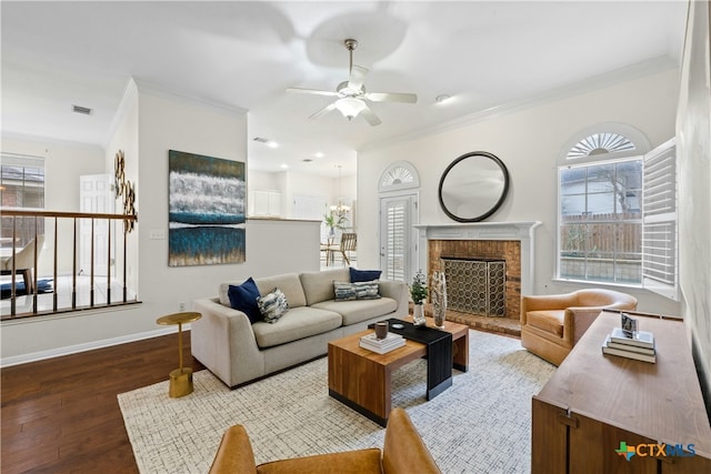 living room with baseboards, visible vents, wood finished floors, crown molding, and a fireplace