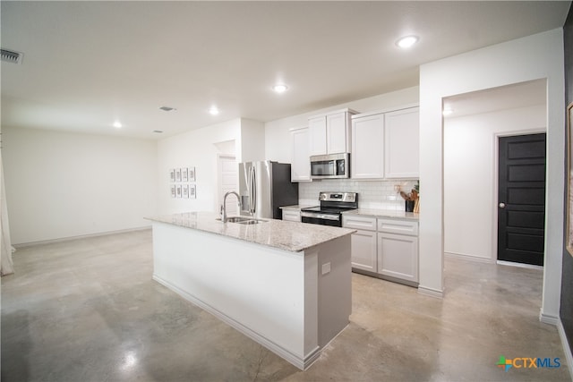 kitchen with white cabinetry, appliances with stainless steel finishes, tasteful backsplash, and an island with sink