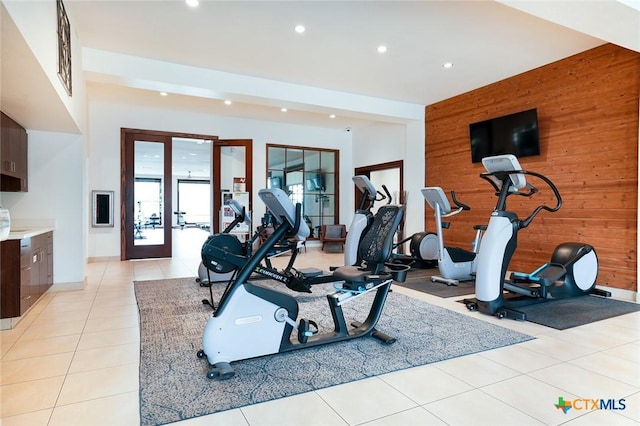 exercise room with recessed lighting, french doors, wood walls, and light tile patterned floors