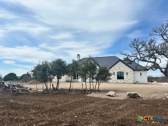 exterior space featuring stone siding and metal roof