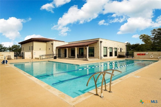 community pool with a patio and fence