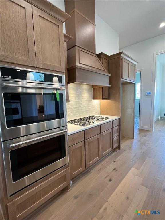 kitchen with recessed lighting, premium range hood, a spacious island, backsplash, and dark stone counters