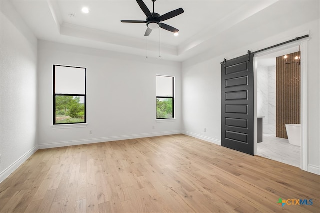 1123 Vintage Way, New Braunfels, TX 78132 - empty room with a barn door, a tray ceiling, light wood-style flooring, a ceiling fan, and ornamental molding
