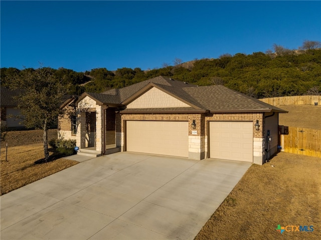 single story home with a garage, driveway, a shingled roof, and brick siding