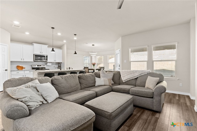 living area with dark wood-style floors, baseboards, visible vents, and recessed lighting