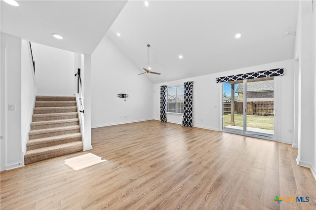 unfurnished living room featuring stairs, high vaulted ceiling, light wood-style floors, and a ceiling fan