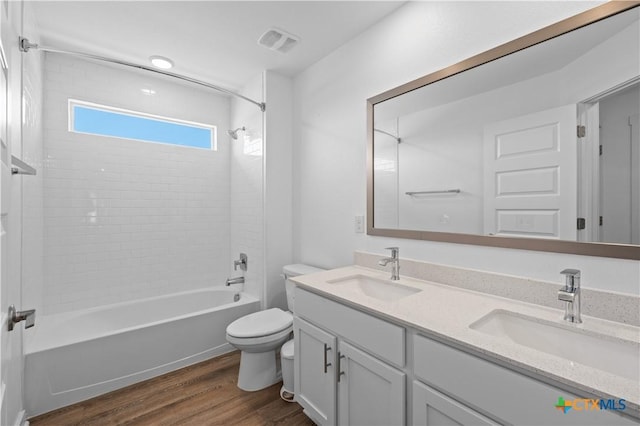 full bathroom featuring toilet, a sink, wood finished floors, and visible vents