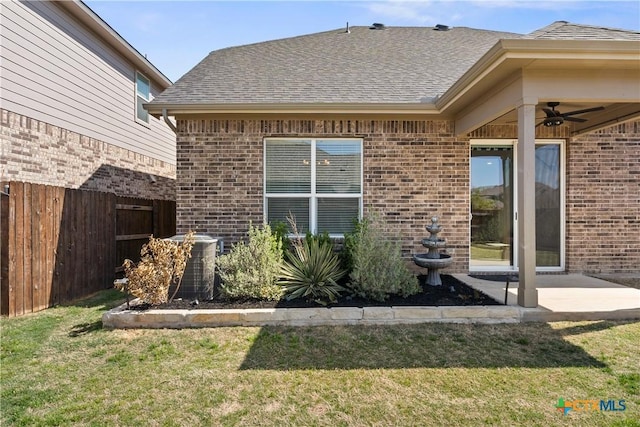 rear view of property featuring brick siding, fence, and a lawn