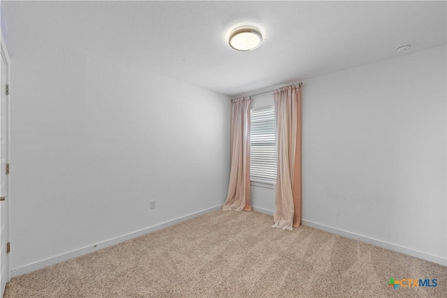 unfurnished room featuring light carpet and baseboards