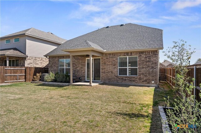 back of property featuring a fenced backyard, brick siding, and a yard