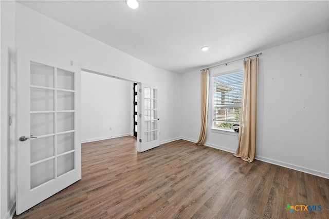 unfurnished room featuring baseboards, wood finished floors, and french doors