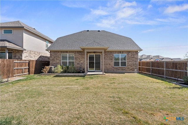rear view of house with a fenced backyard, a lawn, and brick siding