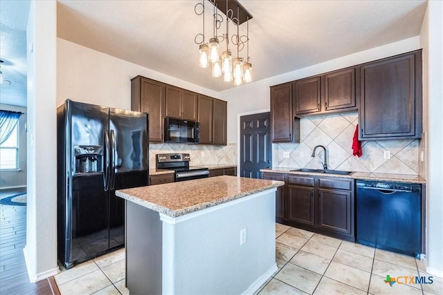 kitchen with pendant lighting, black appliances, sink, a kitchen island, and dark brown cabinetry